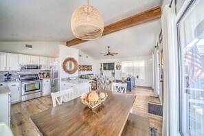 Una cocina amplia con armarios blancos, una mesa de comedor de madera y una lámpara colgante.