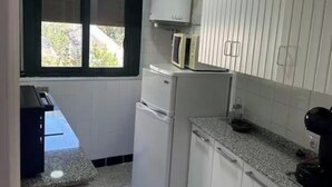 A compact kitchen with white cabinets, a refrigerator, a microwave, and a coffee maker.