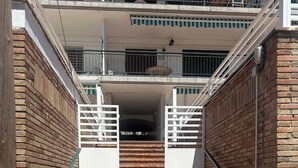 A set of outdoor brick stairs leading to a gated entrance, flanked by brick walls and metal railings.