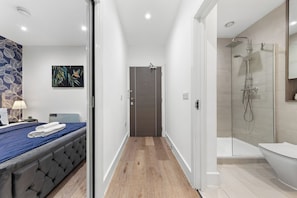 A modern hotel room with a bed, a shower area, and a bathroom.