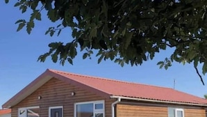 Et etplans træhus med rødt tag, en hoveddør og to vinduer.