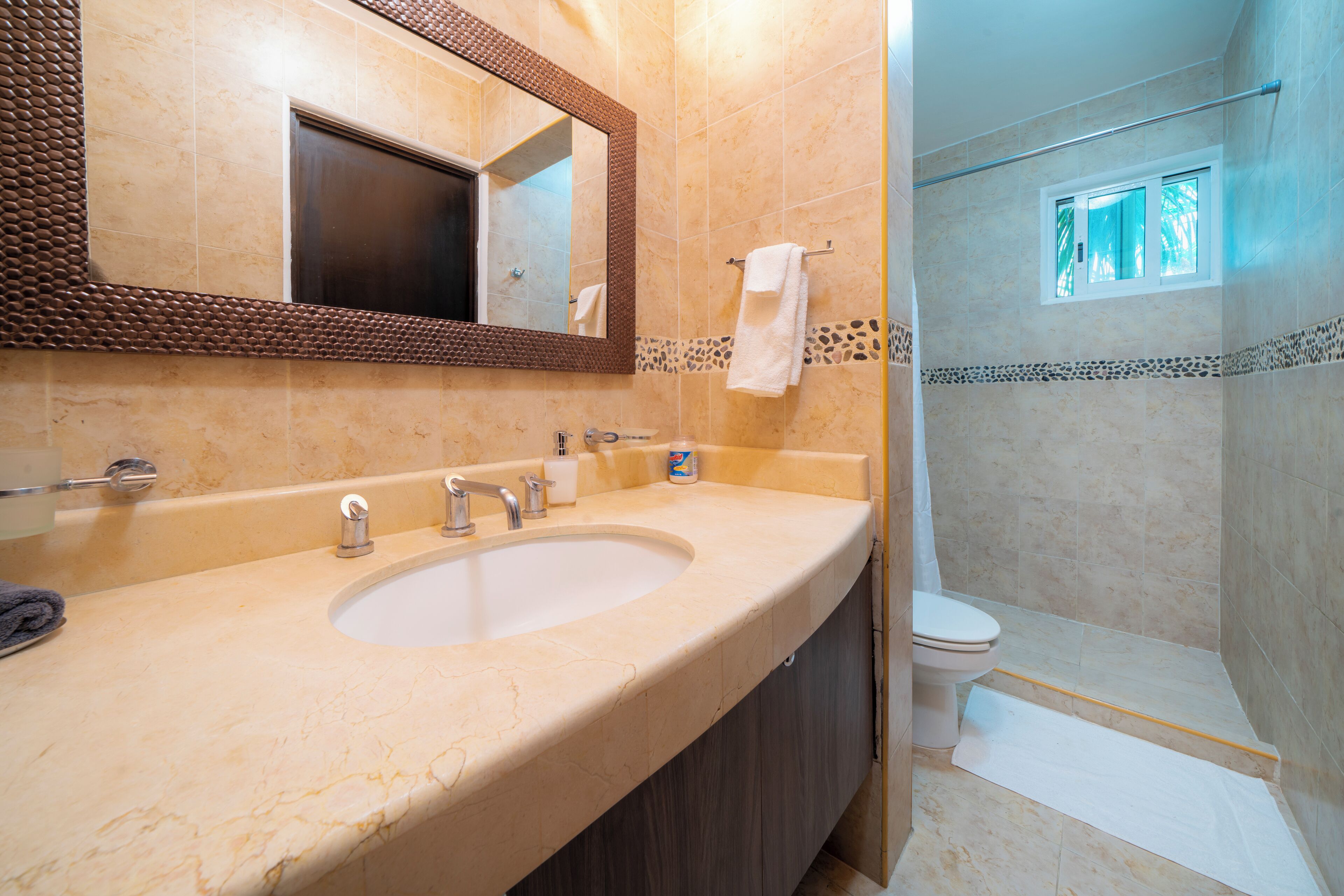 A bathroom with a large sink, a mirror, and a shower area.