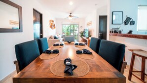 A dining area with a wooden table set for four, surrounded by chairs.