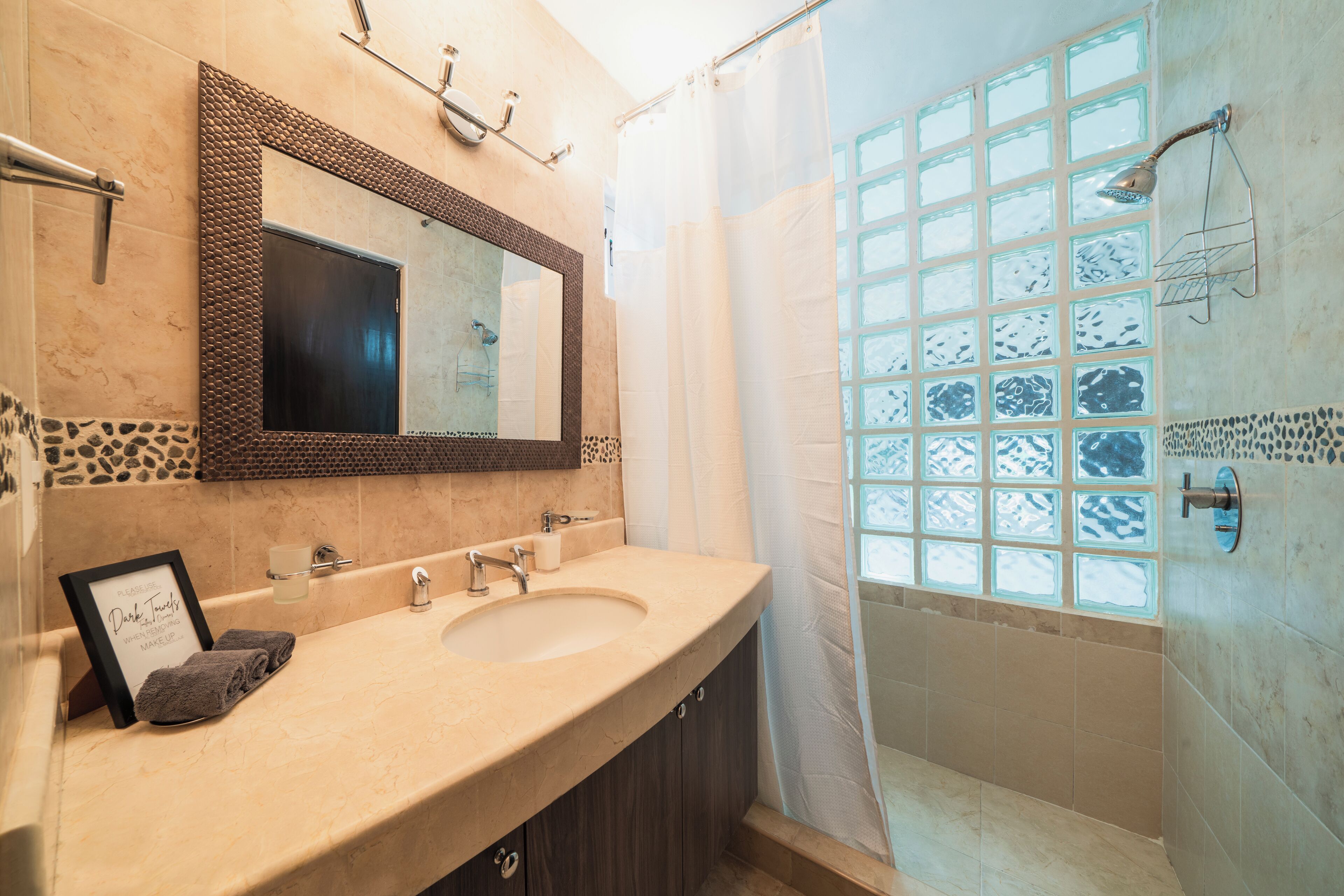 A bathroom with two sinks, a large mirror, a shower with a glass door, and a towel rack.