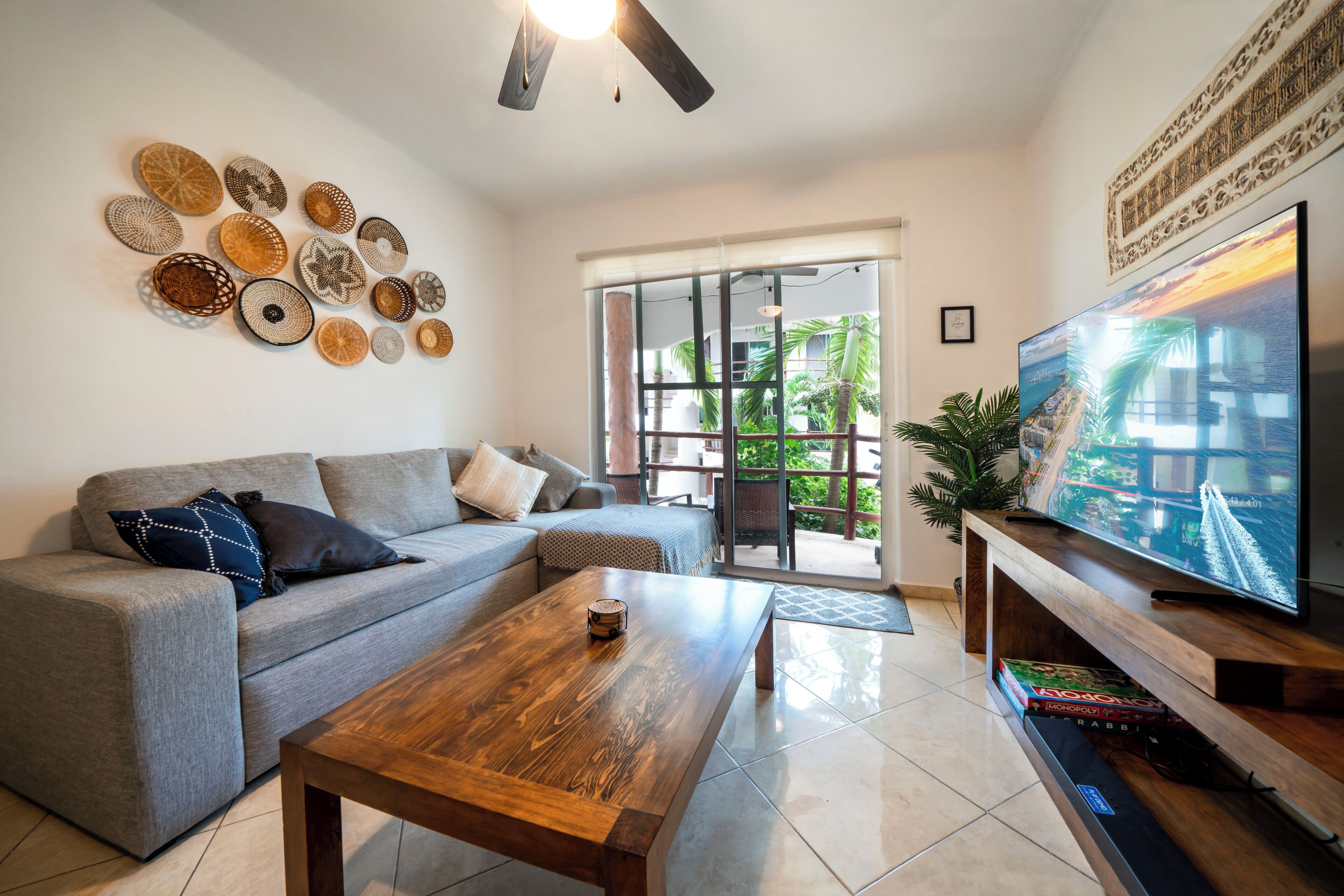 A living room with a grey sofa, wooden coffee table, and a flat-screen TV on a wooden stand.