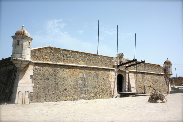 A historic stone building with a large arched entrance, a small tower, and a flagpole. - Spectacular Lagos Marina View apt on Promenade (Lagos)