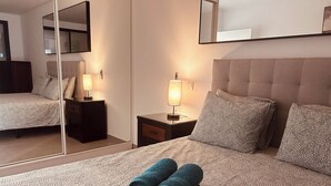 Une chambre d’hôtel avec un lit, deux tables de chevet, un miroir et une lampe.
