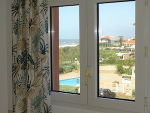 A room with a large window overlooking a pool and a residential area. - 1 Bedroom Apartment in Anglet (Anglet)