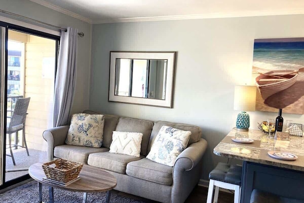 A cozy space featuring a light gray sofa adorned with nautical-themed throw pillows.