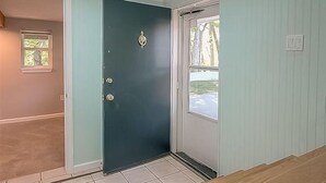 A room with a dark door, light walls, and a window.