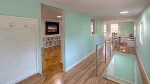 A spacious living area with a wooden floor, a TV, and a dining area with a table and chairs.