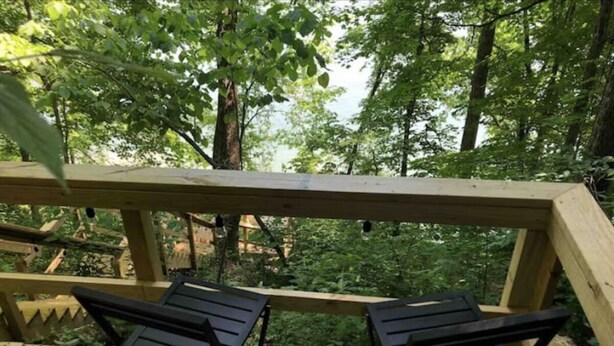 A wooden deck with two black chairs and a wooden railing.