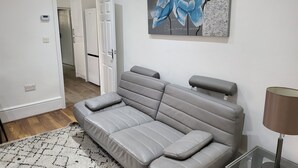 A modern living room with a grey sofa, a patterned rug, and a painting of blue flowers on the wall. - Inviting Entire 1-bed Apartment in Reading (Reading)