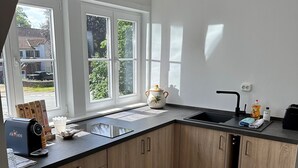 A modern kitchen with wooden cabinets, a black countertop, and a window overlooking a residential area. - Apartment in Buchholz in der Nordheide, Germany (Buchholz in der Nordheide)