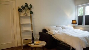A bedroom with a bed, bedside table, and a plant on a shelf. - Apartment in Buchholz in der Nordheide, Germany (Buchholz in der Nordheide)