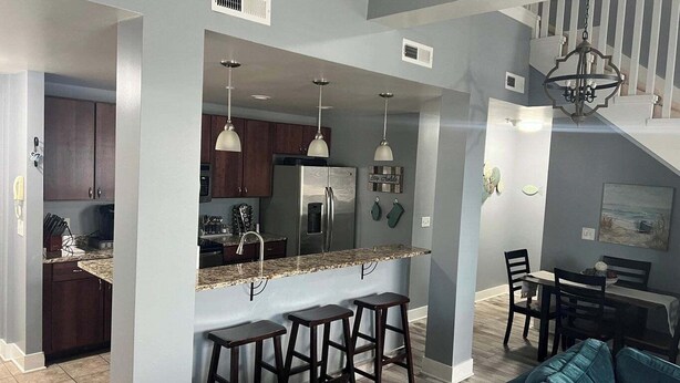 Una cocina moderna con una isla central, taburetes de bar y una zona de comedor con mesa y sillas.
