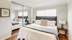 A bedroom with a large bed, a mirror, bedside tables with lamps, and decorative wall art. - Peaceful Poway Vacation Rental Near Shops & Dining (Poway)