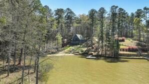 Une maison entourée d’une forêt, bordée par un plan d’eau et dotée d’un quai.