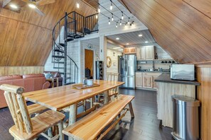 Ein geräumiges Loft mit einem Holzesstisch, Bänken, einer Treppe und einer Küchenzeile.