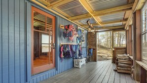 Une cabane en bois avec un porche, un porte-manteau fixé au mur et une porte en bois.
