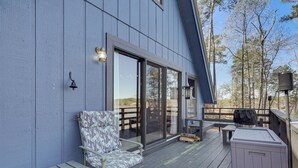Une terrasse avec une chaise, une table et un barbecue.