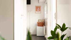 Un lavadero con lavadora, una cesta y un cuadro en la pared.