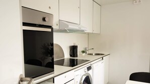 Una cocina compacta con horno empotrado, lavadora, fregadero y cafetera.