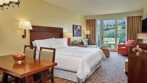 A hotel room with a large bed, a desk, a dining table, and a balcony with a view of the countryside. - The Westin Riverfront Mountain Villas, Beaver Creek Mountain Studio
 (Avon)