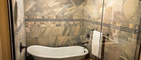 A bathroom with a freestanding bathtub, a shower, and a small wooden stool.