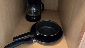 A kitchen cabinet with a pot on the top shelf, a coffee maker on the middle shelf, and a frying pan on the bottom shelf. - Midtown Condo right on Main St! Walking distance to everything! (Lava Hot Springs)
