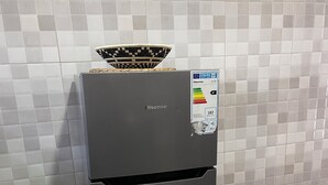 Un refrigerador Hisense con pantalla digital de eficiencia energética, ubicado en una cocina con paredes de azulejos.
