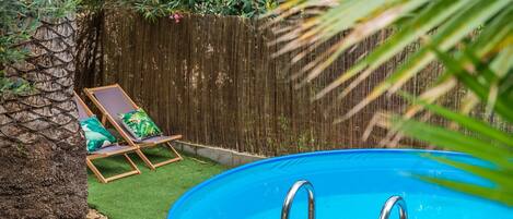 Un jardin avec une piscine, une terrasse en bois et une clôture en bois.