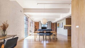 A spacious room with a wooden dining table, chairs, a sofa, and a large window.