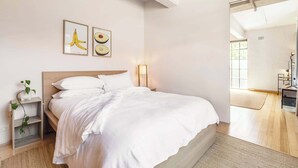 A bedroom with a bed, bedside tables, a lamp, and wall art.