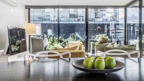 Una sala de estar moderna con una mesa de comedor, sillas y un ventanal con vistas a edificios.