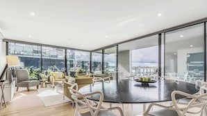 Un comedor moderno con una mesa redonda, sillas blancas y vistas amplias a través de grandes ventanales.