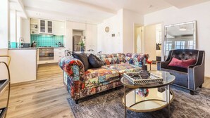 A living room with a sofa, a round coffee table, a black armchair, and a kitchen in the background. - Vintage glamour with indoor pool in heritage CBD (Melbourne)