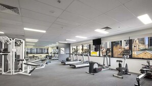 Un gimnasio con cintas de correr, elípticas y equipo de pesas.