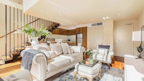 A modern living room with a staircase, a sofa, a coffee table, and a chair.