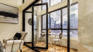 A modern living room with a glass partition, a sofa, a dining table, and chairs.