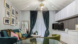 A modern living room with a glass coffee table, teal sofa, and a green armchair.