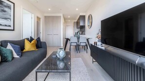 Ein modernes Wohnzimmer mit Sofa, Couchtisch, Fernseher und Essbereich.