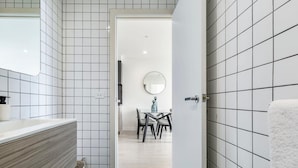 Ein Badezimmer mit weißen Fliesen, einem Holzkosmetikschrank und einem Spiegel.