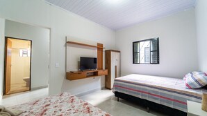 A bedroom with two beds, a TV, and a wardrobe.