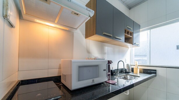 A modern kitchen with a built-in microwave, a kettle, and a sink.