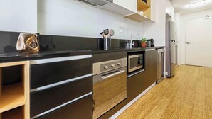 A modern kitchen with stainless steel appliances, wooden cabinets, and a black countertop.