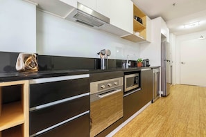 A modern kitchen with stainless steel appliances, wooden cabinets, and a black countertop.