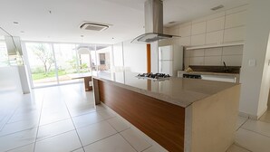 Eine moderne Küche mit einer zentralen Kochinsel, weißen Schränken und einem großen Fenster, das für natürliches Licht sorgt.