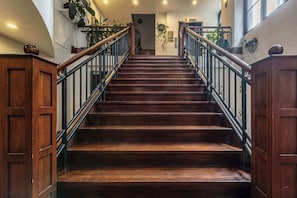 Eine Holztreppe mit schwarzen Geländern und einer Tür oben.
