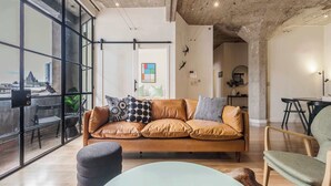 A modern living room with a leather sofa, a round coffee table, and a view through large windows. - Warehouse conversion in historic Dovers building (Melbourne)